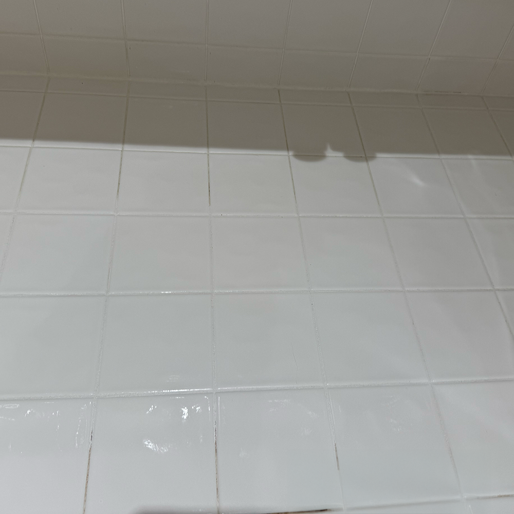 Kitchen tile with discolored and dirty grout lines and t a clean patch, post treatment.